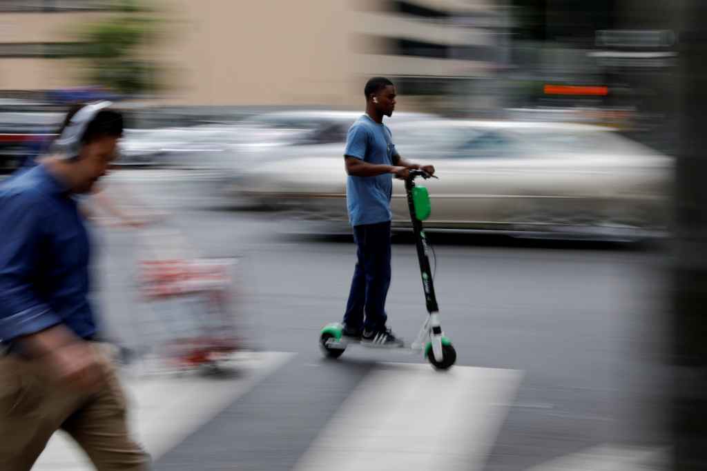 EU. Hombre recorre las calles de Los Ángeles sobre su patín eléctrico mientras los peatones cruzan la calle (Reuters)