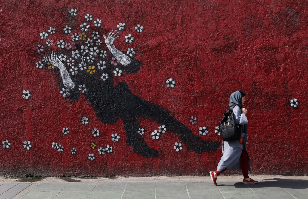 Irán. Joven cruza junto a un mural de flores en el centro de Teherán (AP)