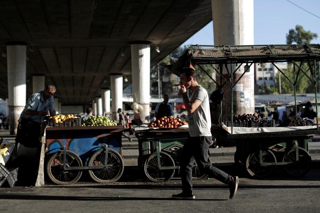 Siria. Un hombre pasa por los puestos de fruta en Damasco que hay en las calles. (AP)
