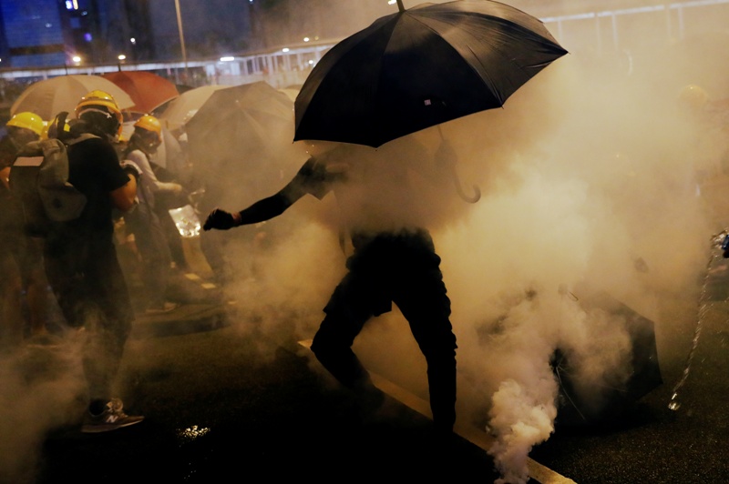 Los manifestantes a favor de la democracia usan paraguas para protegerse de los gases lacrimógenos. (Reuters)