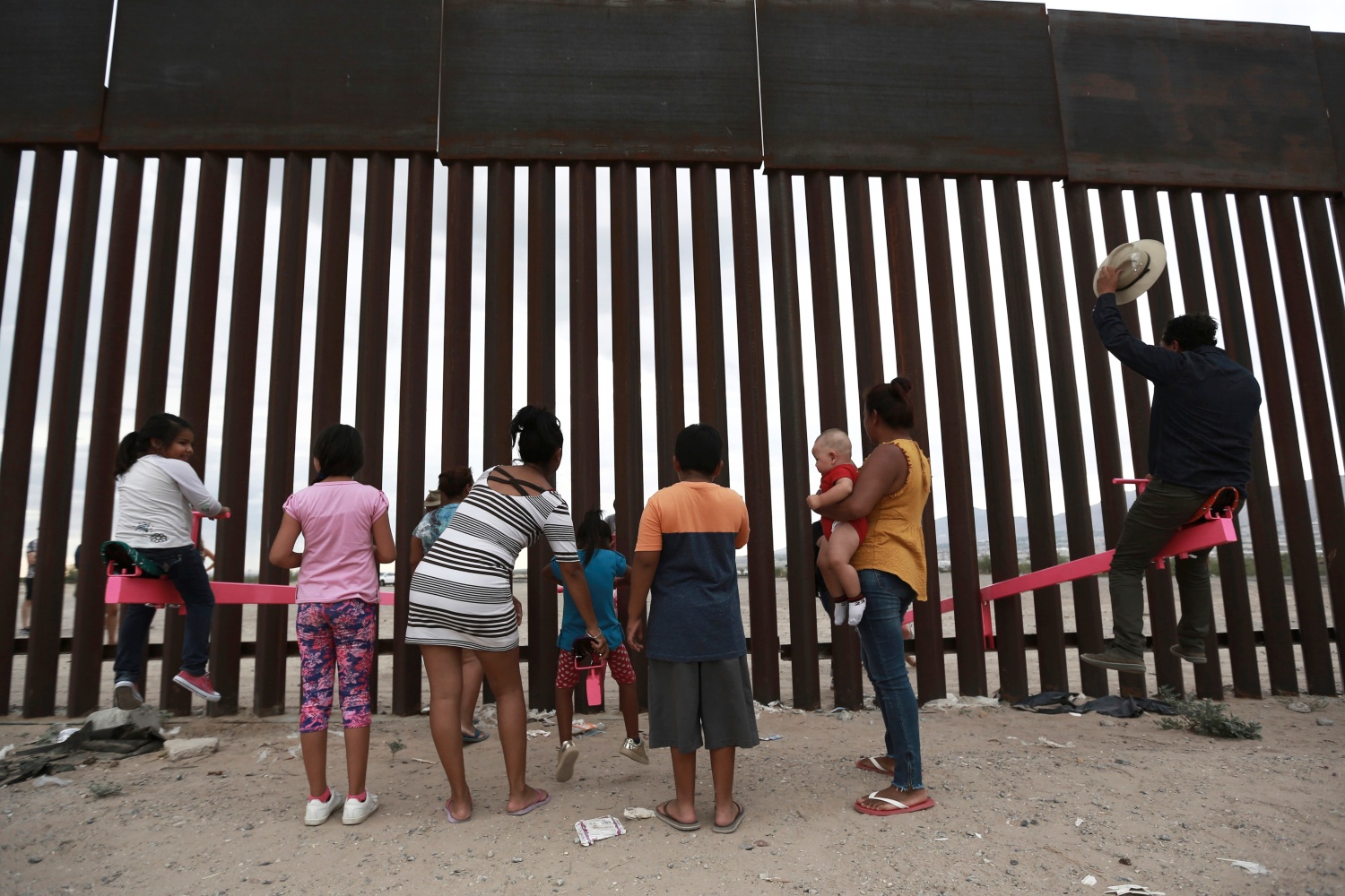 México.- Niños y un hombre juegan en un sube y baja instalado entre el muro fronterizo que divide a México y EU. (AP)