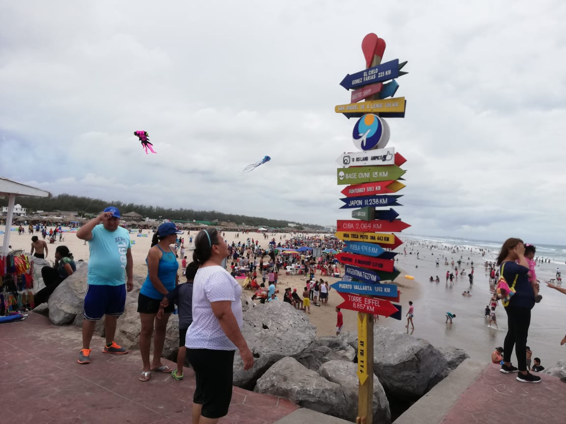 Paseantes observan el tótem de playa Miramar.