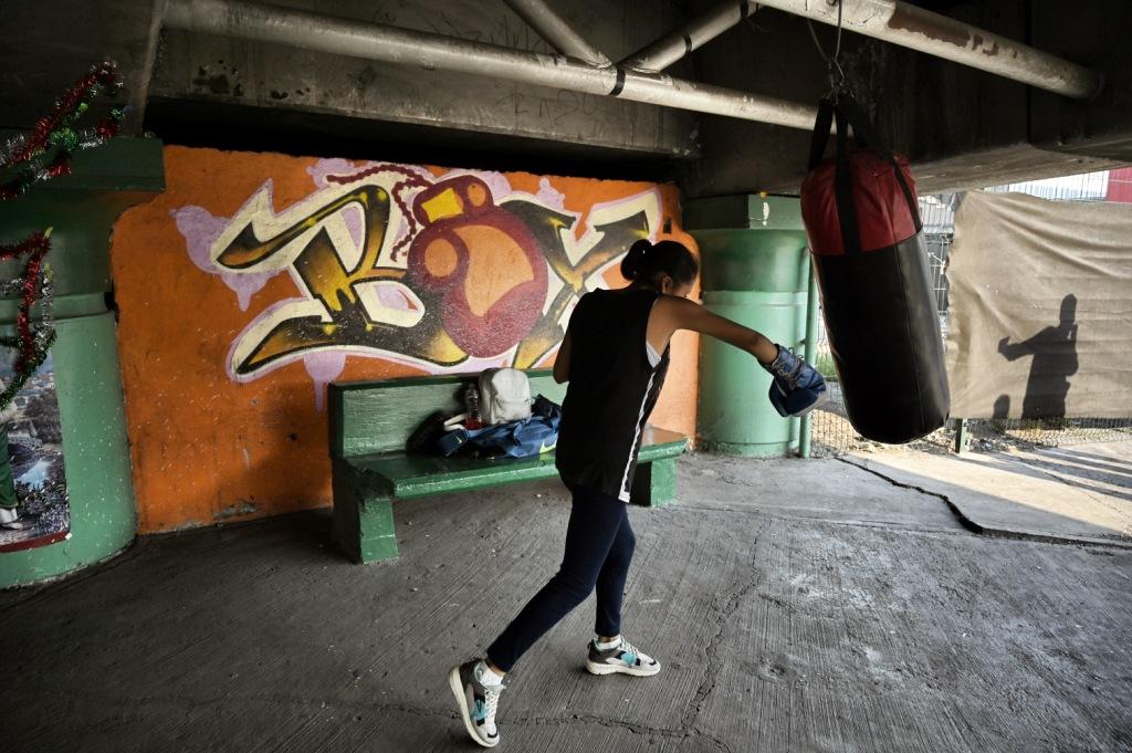 Jóvenes entrenan con un saco de box debajo de un puente vehicular en Ecatepec. (AFP)