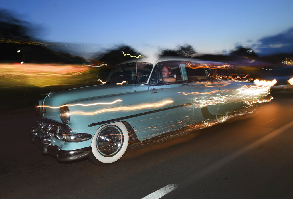 Michigan- Un auto clásico con luces encendidas circula al anochecer sobre Woodward Avenue. AP