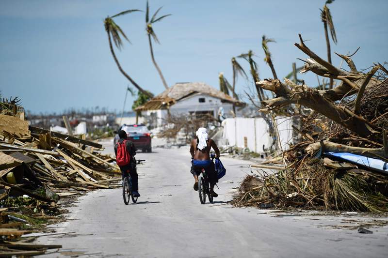 Habitantes de las Bahamas pasan a través de los daños causados por el huracán Doriam. /AFP