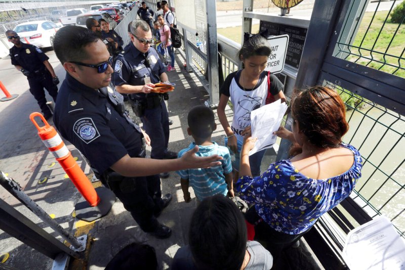 Un agente de la Oficina de Aduanas y Protección Fronteriza verifica documentos de migrantes antes de que sean llevados a solicitar asilo en EU. (AP)