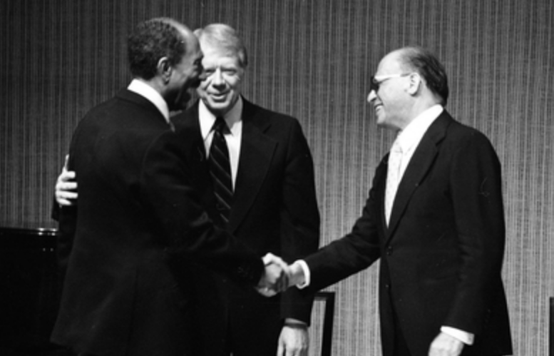 El presidente egipcio Anwar Sadat (izq.) saluda al primer ministro israelí Menachem Begin (der.) en presencia del entonces presidente de EU, Jimmy Car