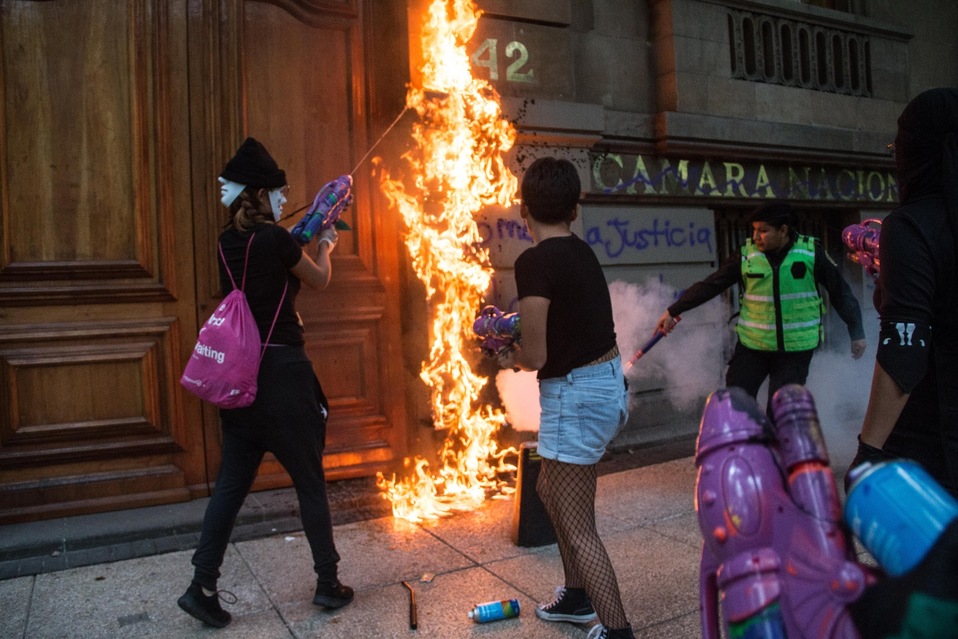 Algunas mujeres con el rostro cubierto quemaron la puerta de la Cámara de Comercio durante la marcha por legalización del aborto. (Cuartoscuro)