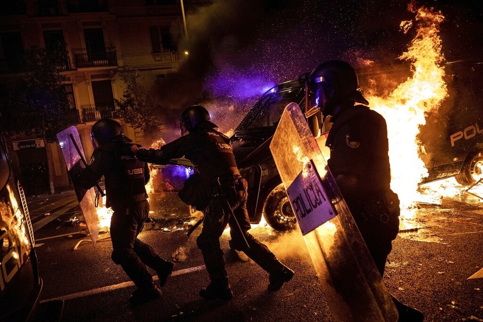 Agentes de policía corren mientras una de sus camionetas cruza una barricada en llamas. (AP)