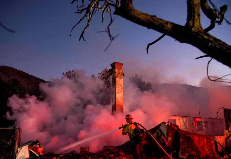 Cientos de bomberos apoyados por helicópteros cisterna atacaban los fuegos alentados por los llamados "vientos de Santa Ana". (AFP)