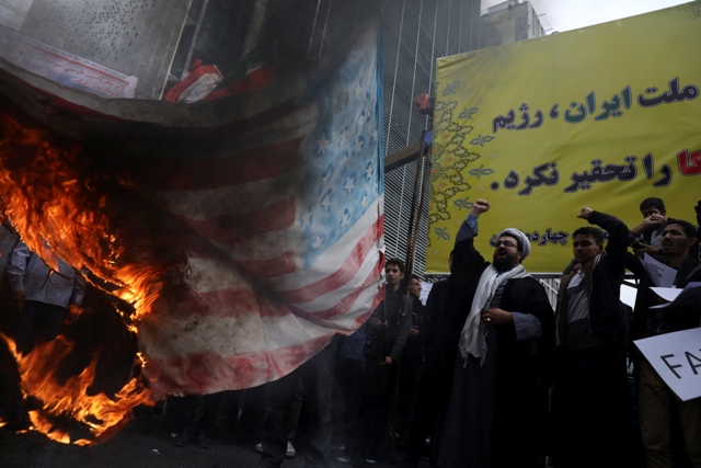 Manifestantes iraníes corean lemas mientras prenden fuego a una representación de una bandera estadounidense, durante una marcha anual ante la antigua