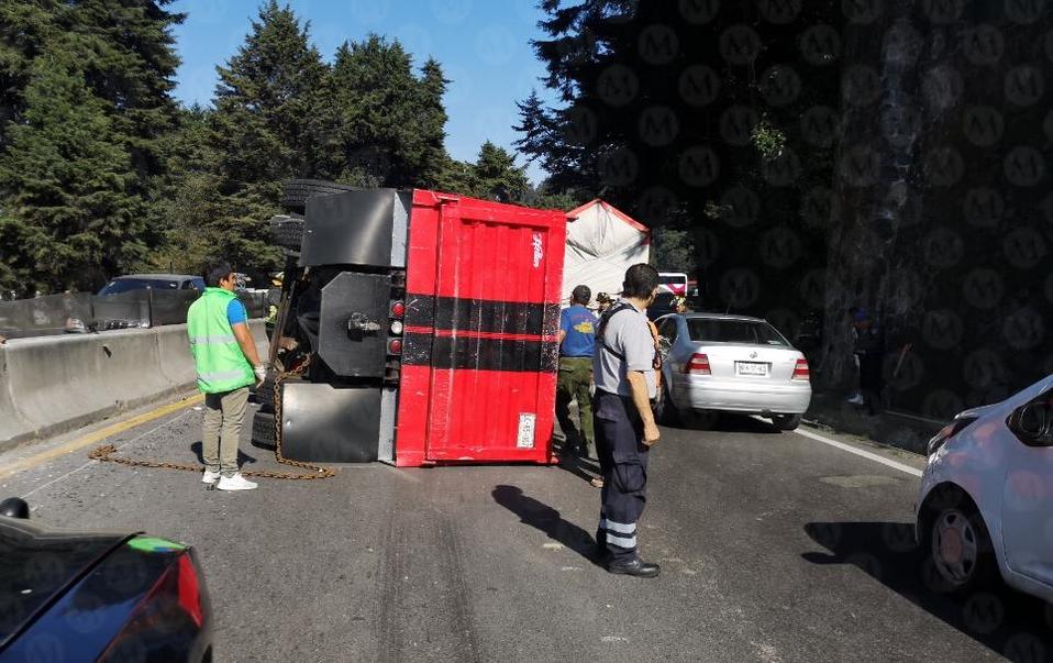 Bomberos y elementos de la Policía Federal están trabajando para retirar del camino el camión que volcó. (Jorge Becerril)