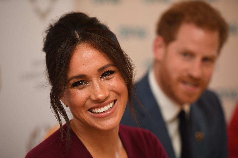 Meghan Markle y su esposo, el príncipe Harry en segundo plano (AFP).