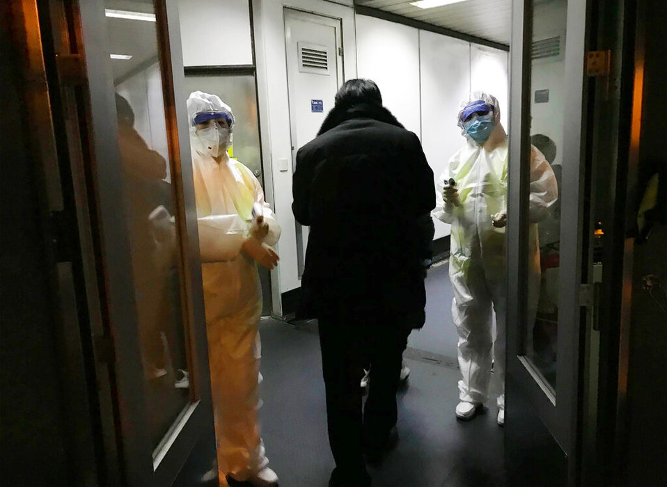 Empleados de salud esperan a la salida de un avión en Pekín para tomar la temperatura de los pasajeros que provenientes de Wuhan. (AP)