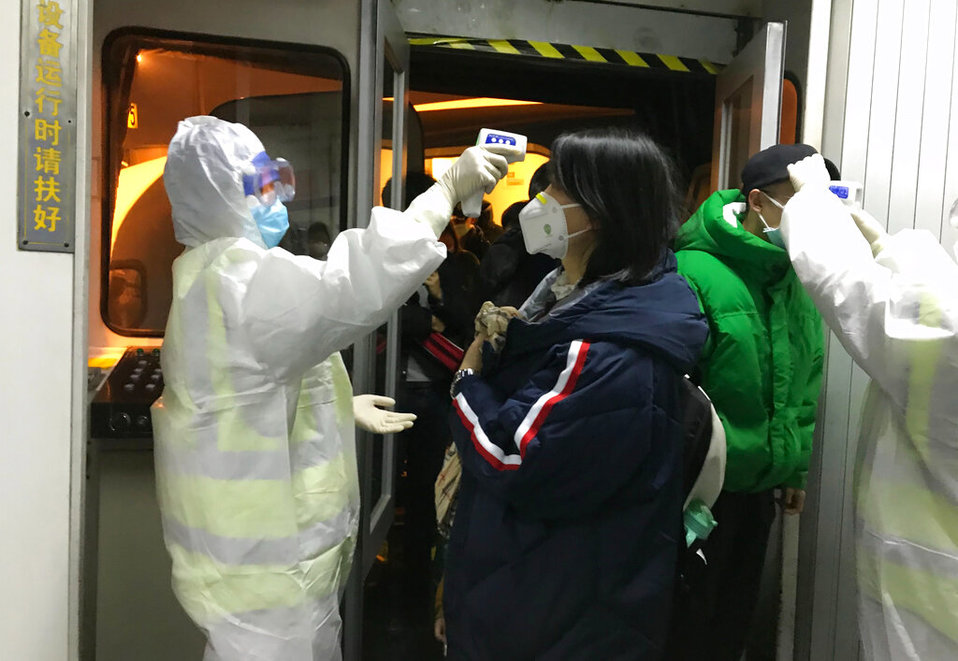 Funcionarios de salud revisan la temperatura corporal de los pasajeros que llegan de la ciudad de Wuhan al aeropuerto de Pekín. (AP)