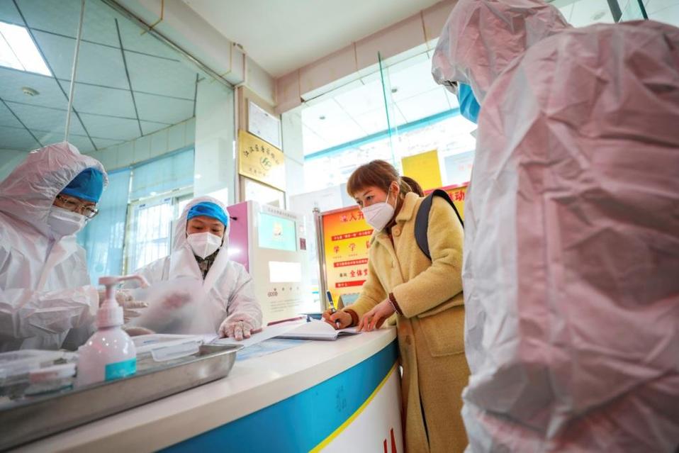Médicos hablan con una mujer que pudiera estar enferma de un coronavirus en Wuhan, China. (AP)
