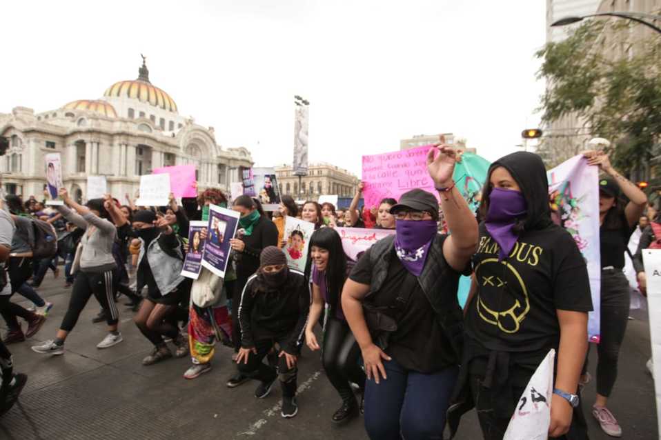 Mujeres encapuchadas gritan consignas durante la marcha. (Avelina Martínez)