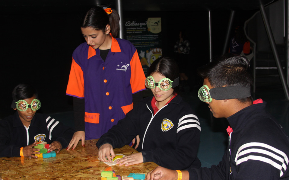 Adolescentes tratando de armar un rompecabezas utilizando lentes de mosca en uno de los módulos del Planetarium Torreón. (Claudia Luévano)