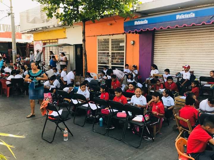 Los niños reciben clases en la calle que está frente a su escuela. (Óscar Rodríguez)