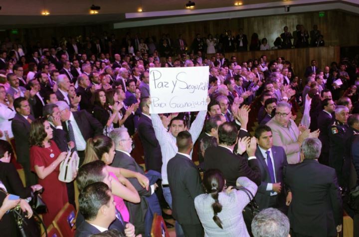 Joven sostiene una cartulina con la consigna "Seguridad y paz para los guanajuatenses", durante el 2do informe de gobierno de Rodríguez Vallejo. Danie