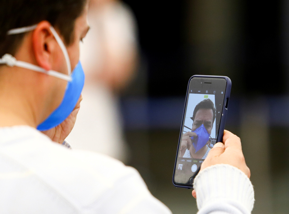 Un hombre con un cubrebocas se toma una foto en su celular (Reuters).
