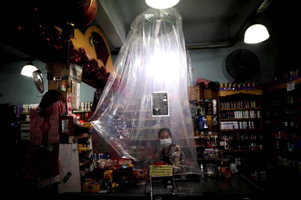 Argentina. Una cajera de supermercado espera a los clientes detrás de una cortina de plástico como precaución contra el coronavirus. (AP)