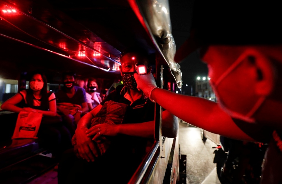 Filipinas. Por Covid-19, un policía verifica las temperaturas de los pasajeros dentro de un taxi colectivo. (AP)