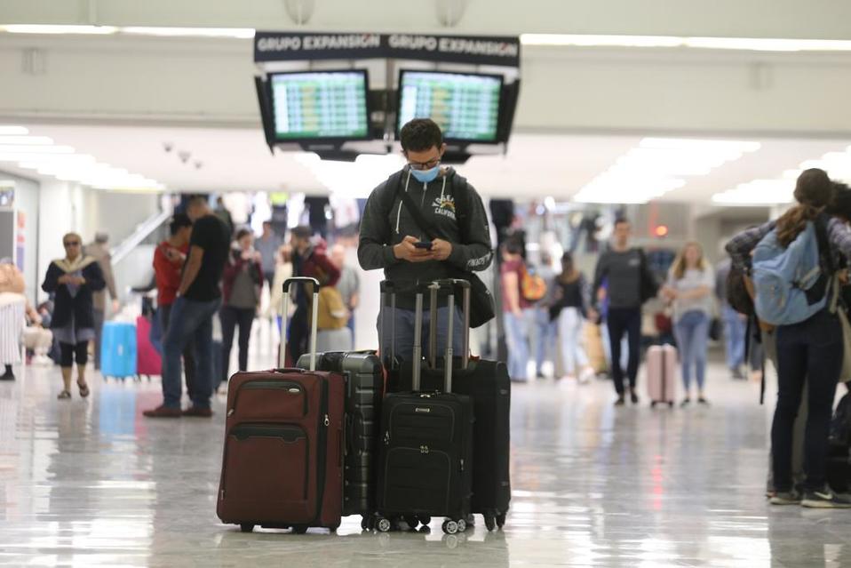 Joven espera en el AICM mientras las autoridades aplican medidas contra el coronavirus. (Jorge Carballo)