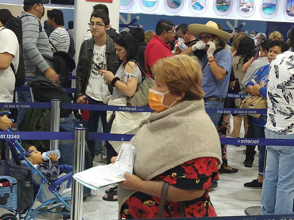 Pasajera lleva cubrebocas por el coronavirus mientras espera en el AICM. (Adyr Corral)