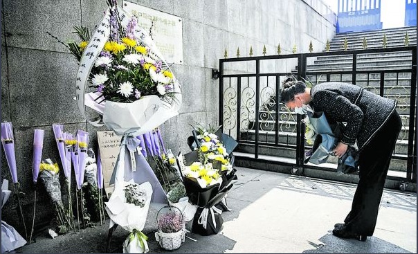 Una mujer deja flores en un altar improvisado en el centro de la ciudad de Wuhan para homenajear a los miles de muertos que causó la pandemia. (AFP)