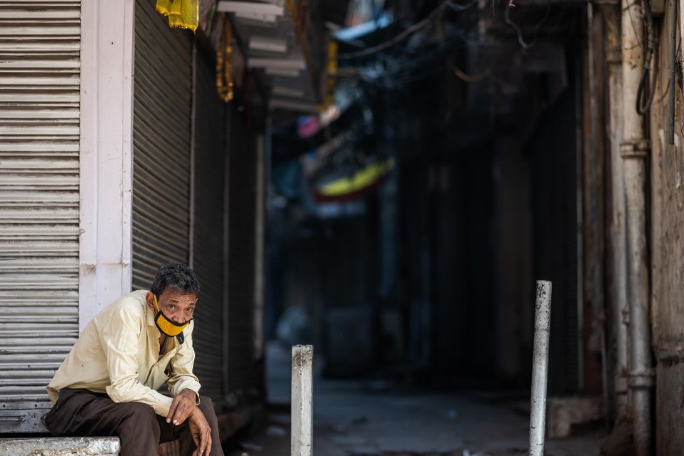 India. Un hombre que usa cubrebocas se sienta frente a una tienda cerrada por el coronavirus. (AFP)