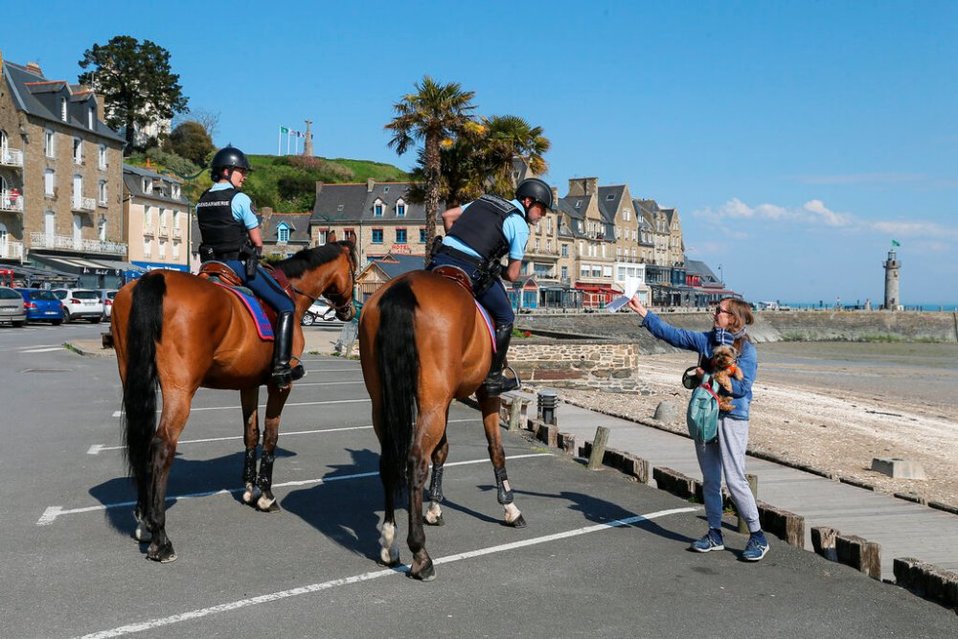 Policías revisan documentos al as personas mientras patrullan las calles durante la cuarentena, en la ciudad costera de Cancale, oeste de Francia. (AP