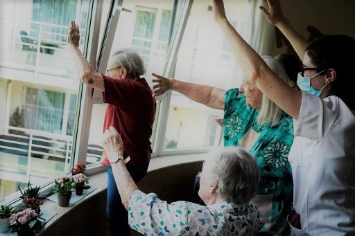 Bélgica. Personas de la tercera edad saludan a sus parientes desde la ventana del asilo. (AFP)