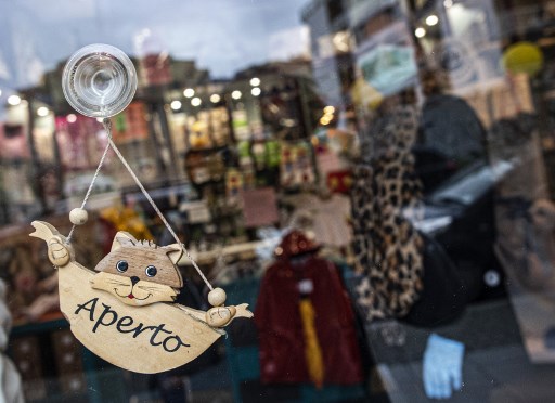 Italia. En la puerta de una tienda de ropa para niños, un señalamiento indica que está abierto. (AFP)
