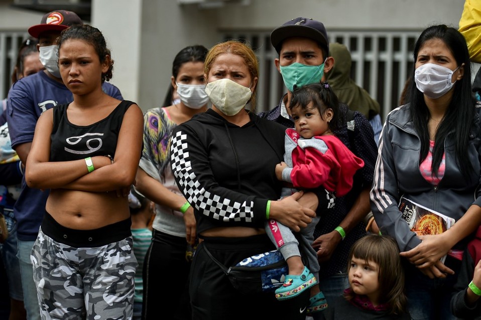 Migrantes venezolanos esperan en Colombia para abordar un autobús que los regrese a su país debido a la pandemia de coronavirus. (AFP)