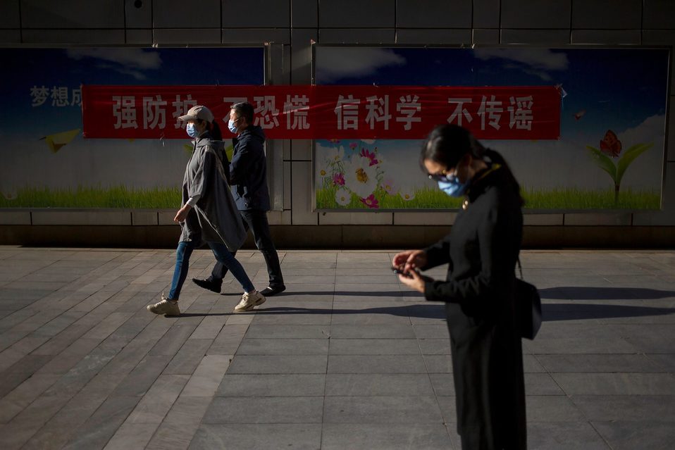 Varias personas caminan por una calle con mascarillas para protegerse del coronavirus en Beijing. (AP)