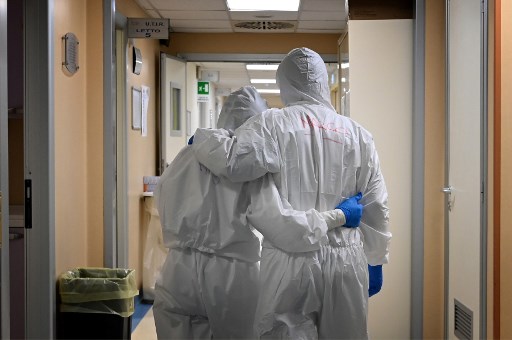 Un doctor y enfermera italianos con equipo de protección se abrazan. (AFP)