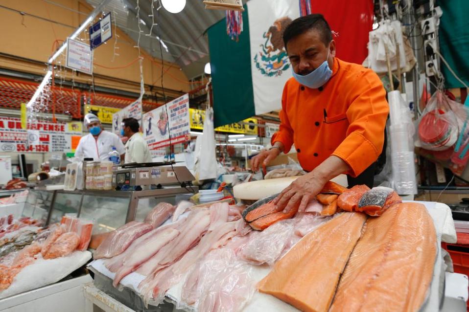 Un comerciante de mariscos utiliza cubrebocas como medida preventiva. (Nelly Salas)