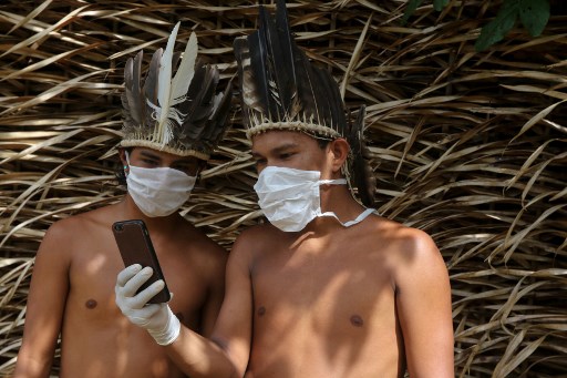 Dos miembros de la comunidad indígena Sateré-Maué del Amazonas usan un teléfono para contactar a un doctor. (AFP)
