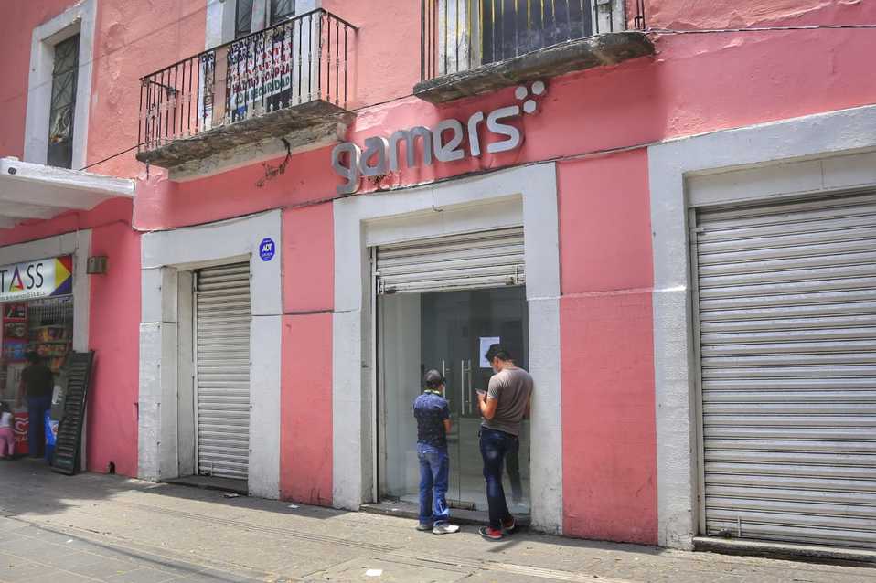 Dos jóvenes esperan en la entrada de una tienda de videojuegos, mientras otros clientes están dentro. (Andrés Lobato)