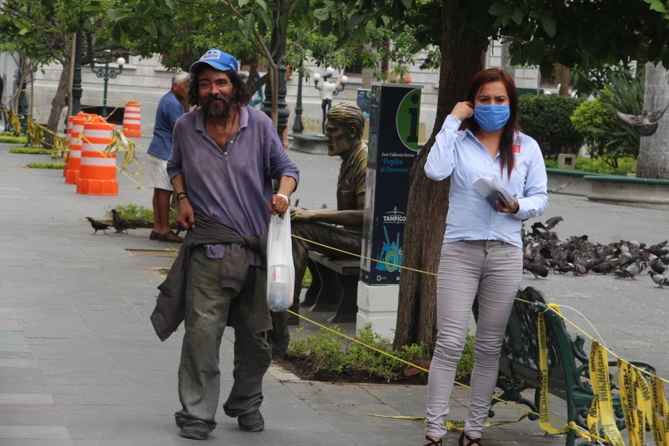Contrastes de la pandemia. Un indigente camina sin cubrebocas por la plaza de Tampico junto a una joven protegida. Yazmín Sánchez