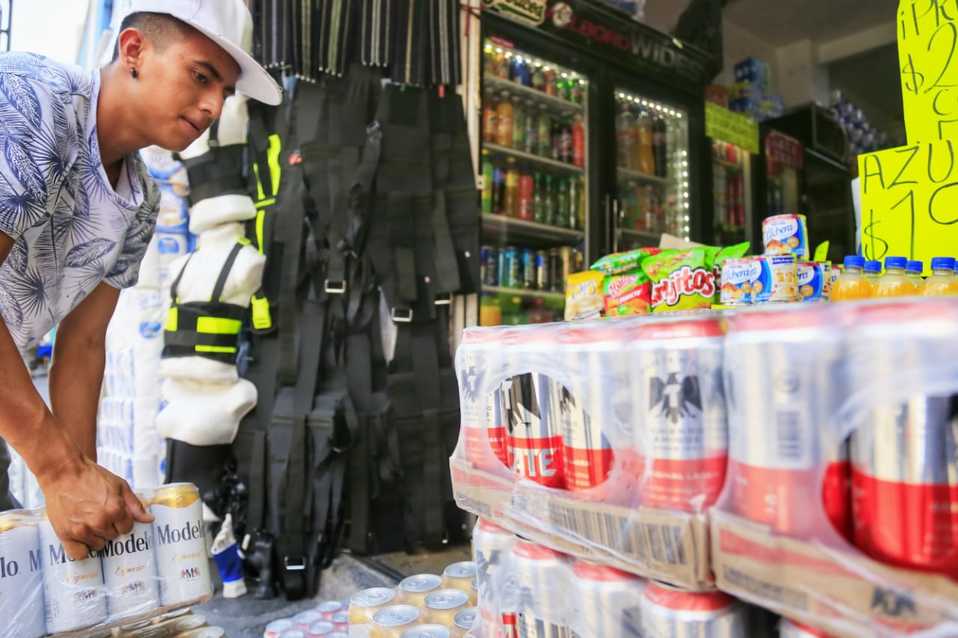 El trabajador de una miscelánea se apresura a introducir a su local planchas de cerveza en el centro histórico. (Andrés Lobato)