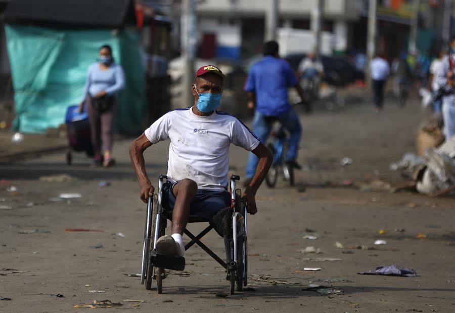 Un hombre en silla de ruedas se desplaza este martes en una plaza de mercado en Cali. (EFE)