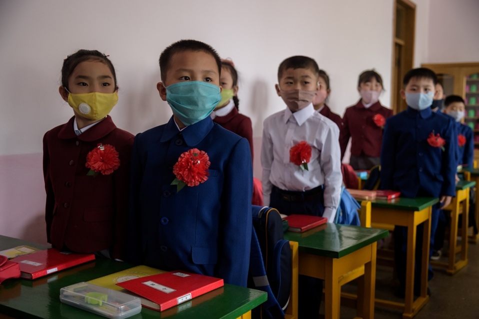 Los alumnos de primaria volvieron hoy a clases, con mascarilla quirúrgica desechables o de tela y flores rojas. (AFP)