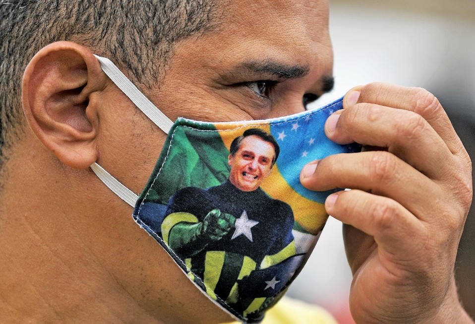 Simpatizante de Jair Bolsonaro usando un cubrebocas con su figura evocando al Capitán América. (AFP)