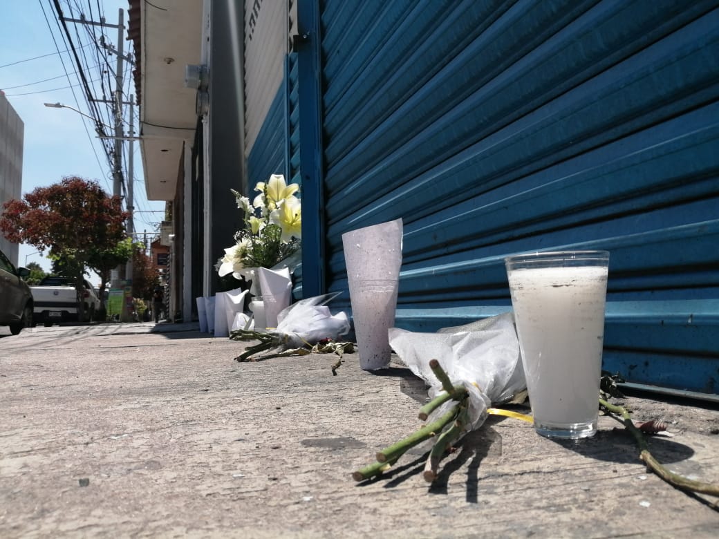 Afuera del taller se pueden ver flores y veladoras que dejan en memoria de los jóvenes asesinados.