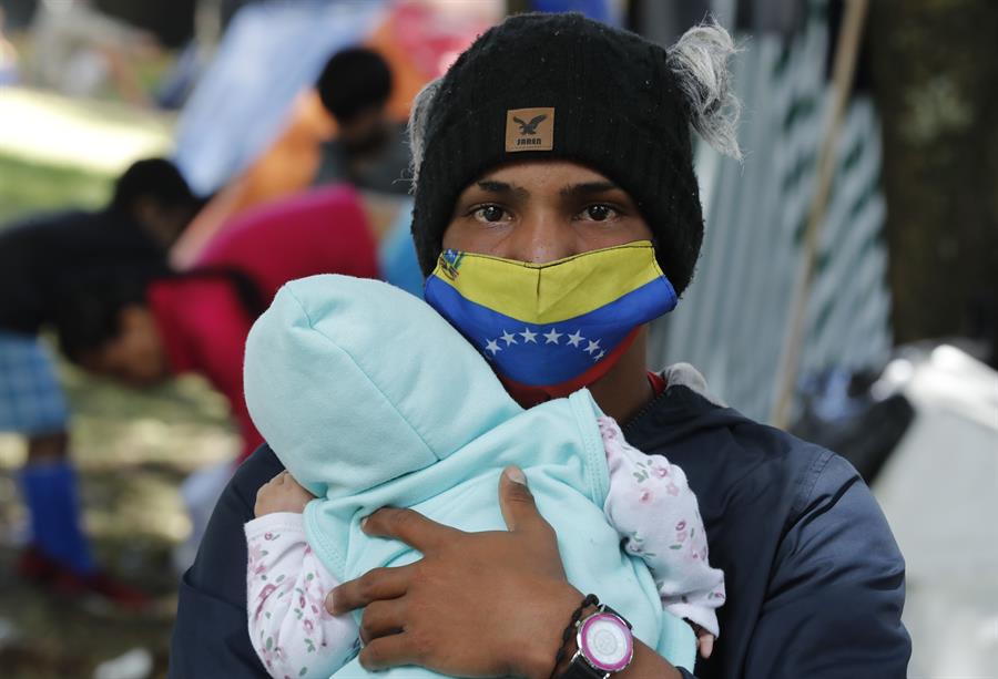 Un ciudadano venezolano sostiene a su hija en un campamento creado hace 13 días. (EFE)