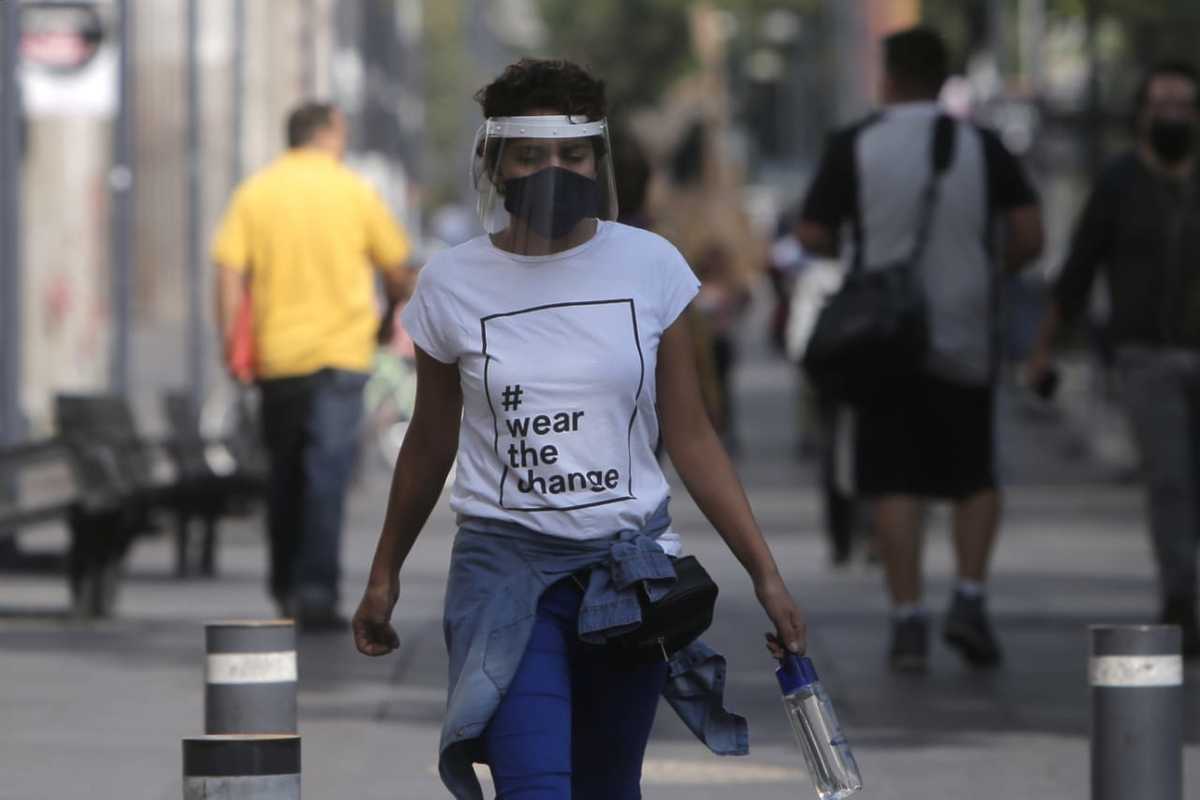 Una mujer con tapabocas y careta camina por la CdMx. (Ariana López)