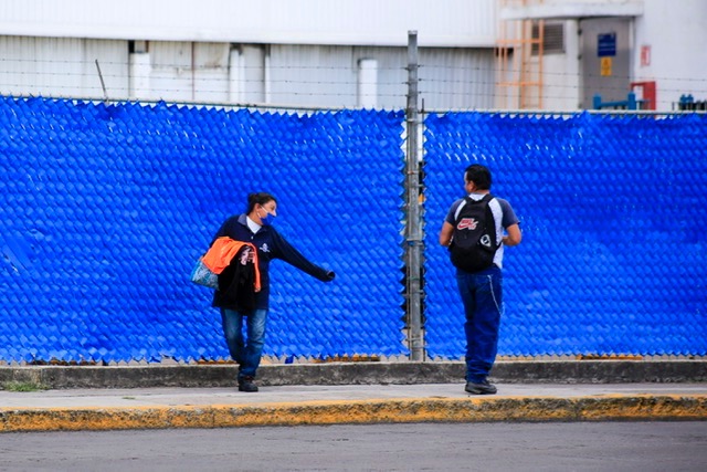 Dos trabajadores de la industria automotriz se saludan en el cambio de turno. (Andrés Lobato)