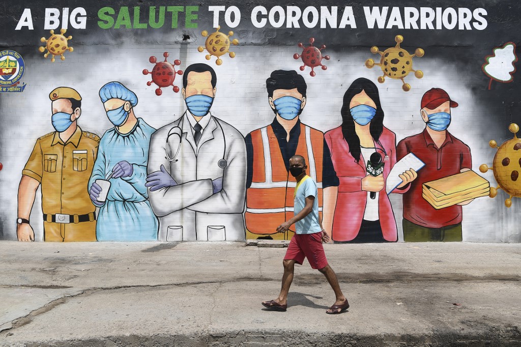 Un hombre camina frente a un mural de "Los héroes de coronavirus", en Nueva Delhi. (AFP)
